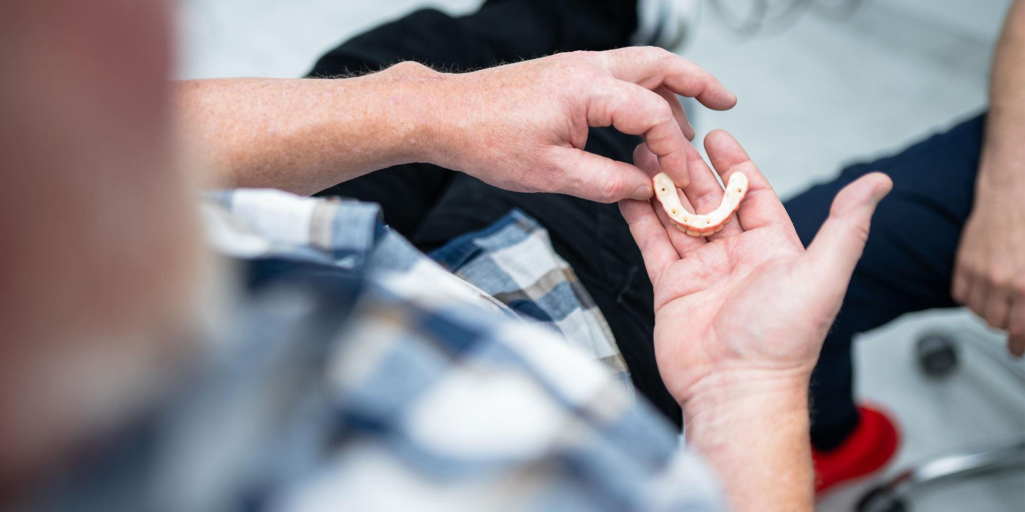 patient holding a full arch model of teeth